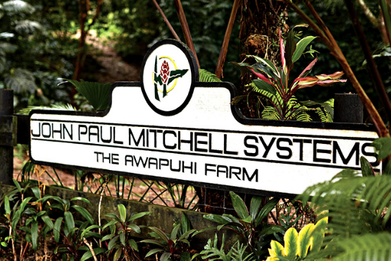 Paul Mitchell Systems Awapuhi farm sign whicih says 'John Paul Mitchell Systems The Awapuhi Farm' the sign is surronded by green, leafy trees